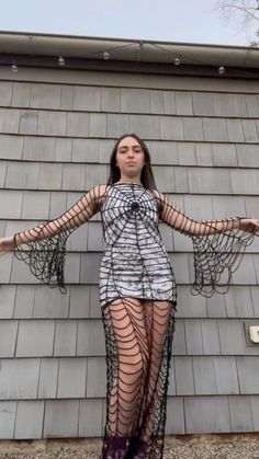 a woman wearing fishnet stockings and holding her arms out in front of a building