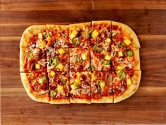 a pizza cut into eight squares on top of a wooden cutting board with cheese and other toppings