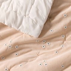 an unmade bed with white and pink comforter on it's side next to a pillow