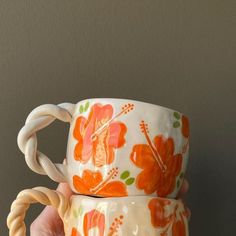 two orange and white coffee mugs sitting on top of each other