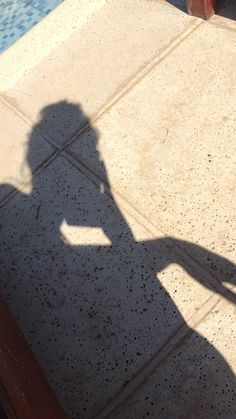 the shadow of a person holding a skateboard in front of a swimming pool area