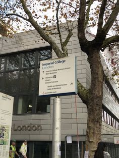 people walking past a building with a large sign on the side of it that reads imperial college london