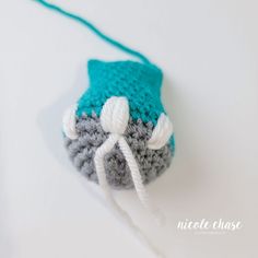 a small crocheted mouse is sitting on a white surface with a green cord