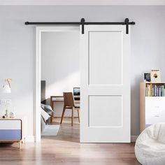 a bedroom with white walls and wooden flooring has sliding doors that open to reveal the living room