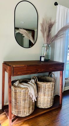 two baskets under a table with a mirror above it and another basket underneath the table