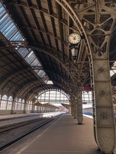 a train station with a clock on the side of it's wall next to tracks