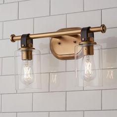 three light fixture with clear glass shades on white brick wallpapered bathroom walls and floor