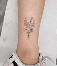 a woman's foot with a small flower tattoo on the left side of her leg