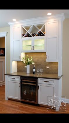 a kitchen with white cabinets and wood flooring is pictured in this image, there are wine glasses on the counter