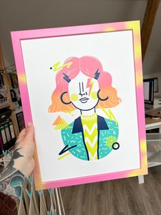 a pink frame with a drawing of a woman's face on it and flowers in the background