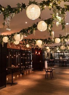 some lights hanging from the ceiling in a room with wooden flooring and greenery