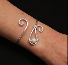 a woman's arm with a silver bracelet on it and a pearl bead in the middle