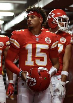 two football players in red and white uniforms are standing together with helmets on their heads