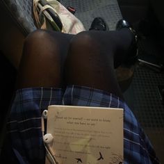 the legs of a person wearing plaid shorts and headphones with a note attached to them