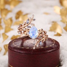 a diamond ring sitting on top of a wooden box with gold leaves around the band