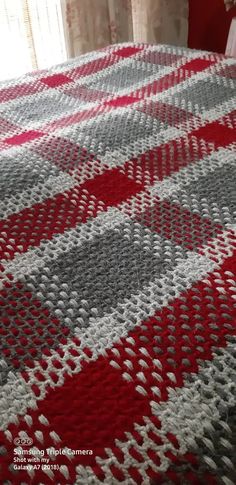 a crocheted blanket on top of a bed next to a red and white pillow