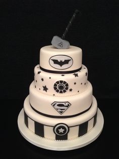 a three tiered cake with black and white stripes on it's sides, topped with a batman symbol