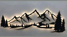 the silhouettes of trees and mountains are shown against a gray sky with sun rays coming through