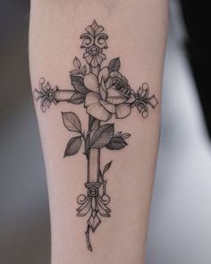 a cross tattoo with roses on it and an arrow around the cross is shown in black ink