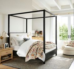 a bedroom with a four poster bed, nightstands and two plants on the side tables