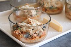 three glass bowls filled with food on top of a white tray next to a piece of cheese