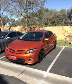 an orange car is parked in a parking lot