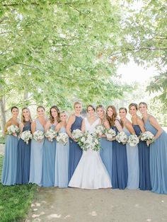 a group of women standing next to each other in front of a green leafy tree