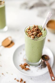 two glasses filled with green smoothie on top of a white plate