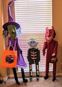 three halloween costumes are lined up in front of a window