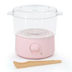 a pink electric cooker next to a wooden spoon