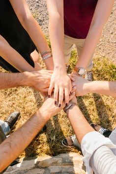 four people holding hands in the middle of a circle