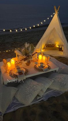 a table set up on the beach with candles