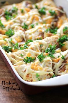 a casserole dish filled with meat and cheese on top of a wooden table