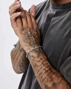 a man with tattoos holding his hands together