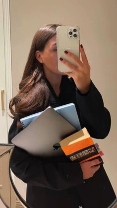 a woman taking a selfie in front of a mirror with books and notebooks