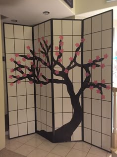 a room divider decorated with pink flowers and a tree painted on the wall behind it