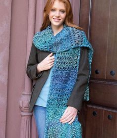 a woman standing next to a brown door wearing a blue scarf