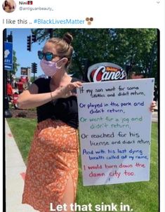 a woman wearing a face mask standing next to a sign