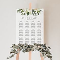 a wooden easer with greenery on it and a seating sign that says, vivien & callum