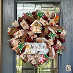 a christmas wreath with gingerbread love written on it and ribbons hanging from the front door