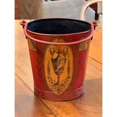 a red bucket sitting on top of a wooden table