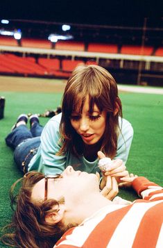 two people laying on the ground with one holding something in his hand and the other looking at it