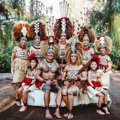 a group of people that are sitting on a bench together in costumes and headdress