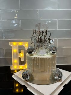 a birthday cake sitting on top of a table next to a light up letter b