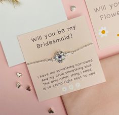 a bridesmaid bracelet with a card attached to it on a pink surface next to other cards