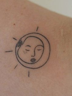 a small tattoo on the back of a woman's shoulder with a sun and moon