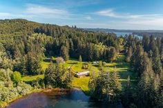 an aerial view of a small cabin in the middle of a forest next to a body of water