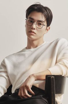 a young man wearing glasses sitting in a chair