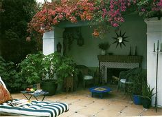 an outdoor living area with potted plants and flowers on the ceiling, along with a fireplace