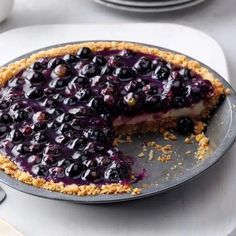 a blueberry cheesecake on a plate with a slice taken out of it and ready to be eaten